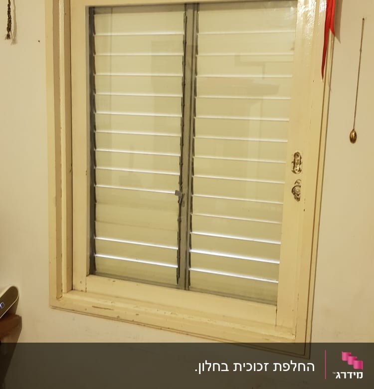 חלון עם תריסים סגורים במסגרת עץ